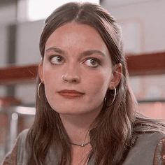 a close up of a person wearing earrings and an orange lipstick color on her lips