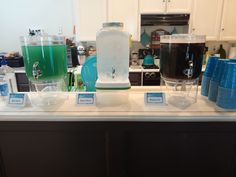 there are many different types of drinks on the counter in this kitchen, including blue and green