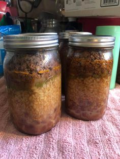 two jars filled with food sitting on top of a pink tablecloth covered table cloth