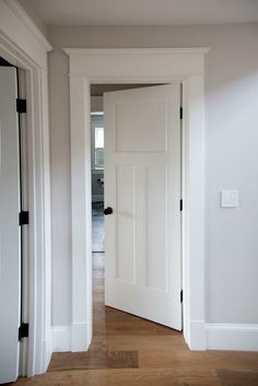 an empty room with white walls and wood flooring is seen from the doorway to the hallway