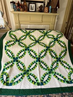 a green and white quilt sitting on top of a bed next to a fireplace mantle