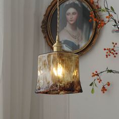 a lamp hanging from the side of a wall next to a framed photo and flowers