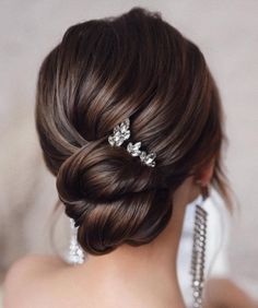 the back of a woman's head with hair combs in her hair and earrings