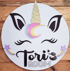 a white circular sign with a unicorn's face and the words tori's room on it