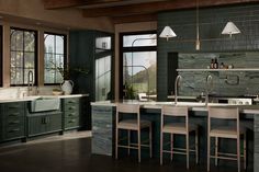 a large kitchen with green cabinets and marble counter tops, along with bar stools