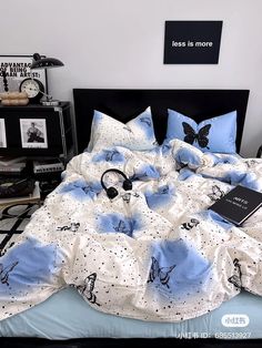 an unmade bed with blue and white sheets, black headphones and books on it