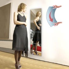 a woman standing in front of a mirror with her hands on the wall looking at herself