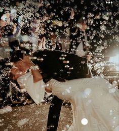 a bride and groom kissing in front of bubbles as they fly through the air on their wedding day