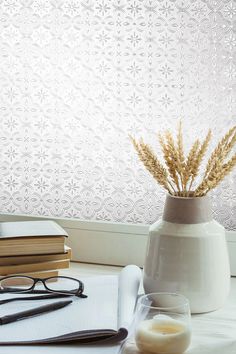 a white vase sitting on top of a table next to a pair of glasses and a book