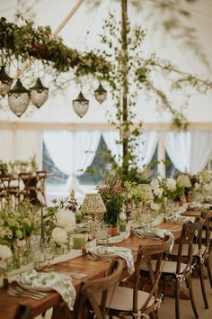 the tables are set up with flowers and greenery for an outdoor wedding reception in a marquee