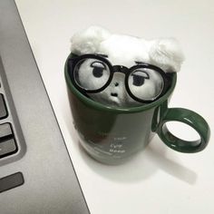 a coffee cup with eyeglasses on it sitting next to a laptop computer keyboard