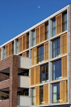 an apartment building with wooden shutters on the front and side windows that are open