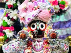 an elaborately decorated figurine is displayed in front of flowers and garlands