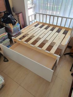 a bed frame made out of wooden slats in a room with tile flooring