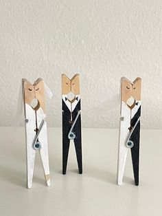 three wooden animals are standing next to each other on a white counter top, one is wearing a tie and the other has a clock