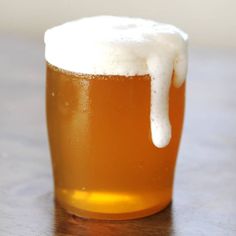 a glass filled with beer sitting on top of a wooden table