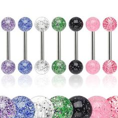 an assortment of different colored jeweled balls with black and silver barbell piercings