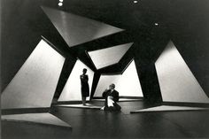 two men sitting on the floor in front of large black and white geometric shapes,