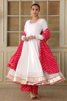 White anarkali with gota work detailing on the neck, sleeves and ghera. Paired with a pink leheriya pattern pant and dupatta. - Aza Fashions White Anarkali Choli With Dabka Work, Anarkali Style White Choli With Dabka Work, White Semi-stitched Churidar For Celebration, Semi-stitched White Churidar For Celebration, White Semi-stitched Anarkali Set, White Anarkali Dress With Gota Work, White Anarkali Set With Resham Embroidery For Celebration, White Anarkali Set With Dupatta For Celebration, White Anarkali Choli In Chanderi Fabric