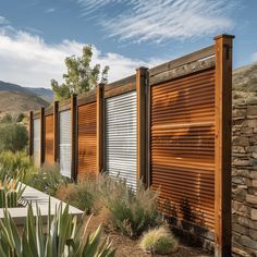 a row of closed garage doors in front of a stone wall and cactus garden with mountains in the background