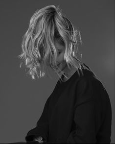 black and white photograph of a woman with her hair blowing in the wind looking down