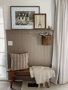 a bench with a blanket on it in front of a window and some pictures above it