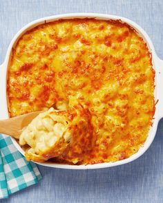 a casserole dish with a wooden spoon in it and a blue checkered napkin