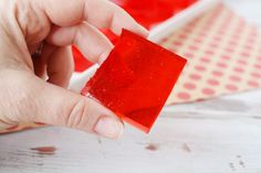 a hand holding a piece of red gummy