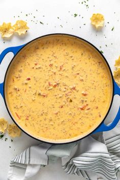 a blue pot filled with soup on top of a white table next to crackers