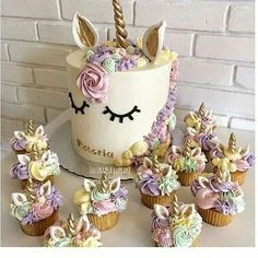 cupcakes with pink and purple frosting are next to a unicorn's head