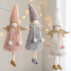 three christmas ornaments hanging from strings in the shape of angels and snowflakes with lights behind them