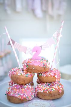 there are donuts with pink frosting and sprinkles on the plate