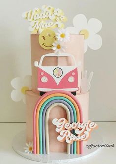 a three tiered cake with a vw bus on top and rainbows in the background