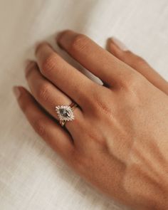 a woman's hand with a diamond ring on top of her left hand,