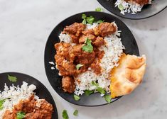 two black plates filled with rice and meat on top of a white marble countertop