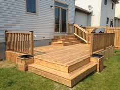 a wooden deck with steps and railings in front of a house