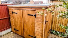 a wooden storage shed sitting in the middle of a yard next to a brick walkway