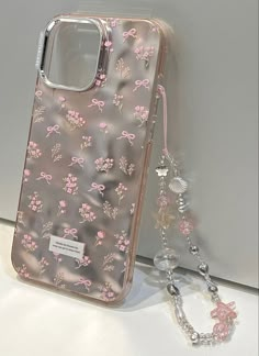 a clear case with pink flowers on it next to a chain