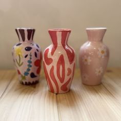 three vases sitting on top of a wooden table