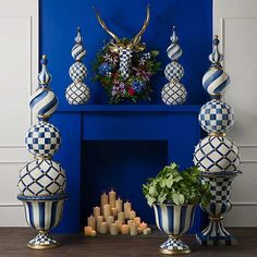 blue and white vases with candles in them on a table next to a fireplace