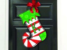 a christmas stocking door hanger hanging on a black door with a red bow