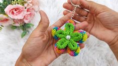 a person holding a crocheted flower keychain