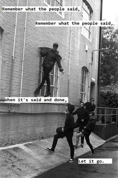 some kids are playing on the side of a building and one is kicking another kid