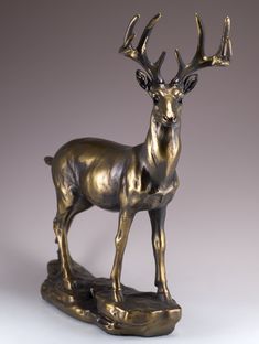 a bronze statue of a deer standing on a rock