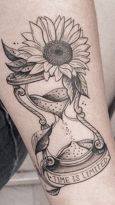 a woman's leg with a sunflower and an hourglass tattoo on it