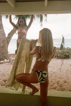 two women in bikinis hanging out on the beach