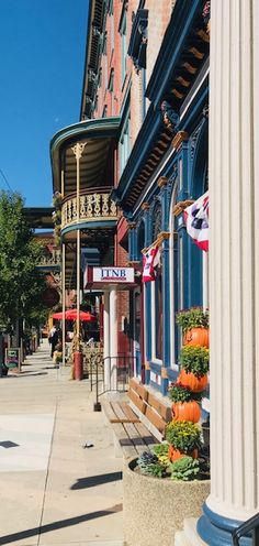 the corner of a street with many buildings and flags hanging from it's sides