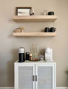 two wooden shelves above a white cabinet with coffee cups and mugs on it,