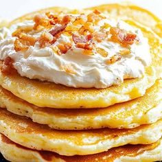 stack of pancakes topped with whipped cream and bacon