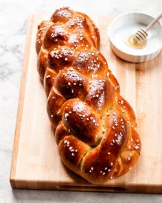 two loaves of bread sitting on a cutting board next to a bowl of honey